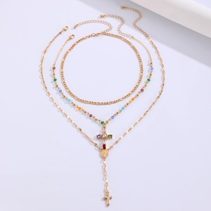Detail of layered gold-tone Y-necklace with multi-colored beads and cross pendant
