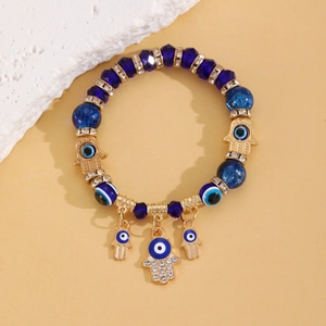 Détail des perles bleues œil maléfique et breloque main de Hamsa sur bracelet perlé