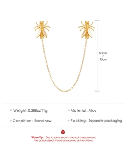 Macro detail of gold-tone alloy bee chain brooch featuring polished wings and fine tassel