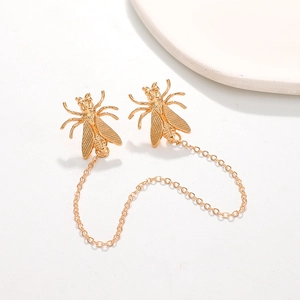 Golden cicada insect brooch with chain fringe and metallic wing detail on white backdrop