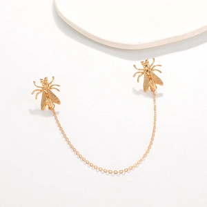 Detailed close-up of golden insect lapel pins connected by a fine metal tassel chain