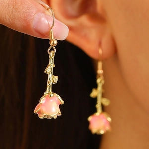 Vintage pink rose earrings with golden stem and leaf design on female model