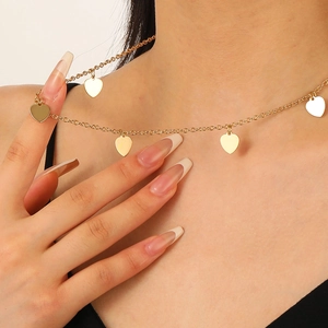 Nahaufnahme einer goldenen zweischichtigen Halskette mit fünf Herzanhängern am Model