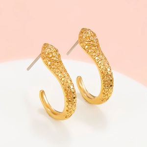 Détail de boucles d'oreilles créoles serpent dorées avec design en zircons micro-pavés