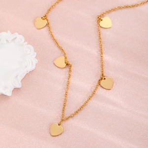 Detail einer goldene zweilagigen Kette mit fünf polierten herzförmigen Anhängern