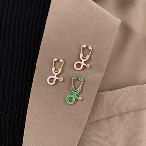 Cartoon stethoscope lapel pins in white, pink, and green on a brown suit lapel
