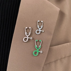 Detailed close-up of stethoscope enamel pins in pink, green, and white on a brown blazer