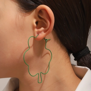 Primer plano de una modelo con aretes de aro verdes grandes con forma de flor irregular