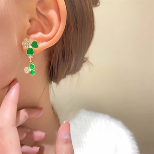 Primer plano de modelo con pendientes de trébol en oro con esmalte verde y cristales