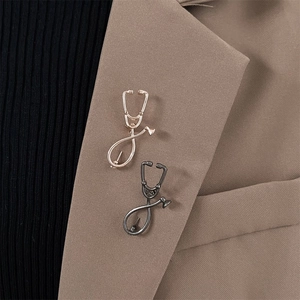 Broche de estetoscopio en esmalte oro rosa y bronce sobre la solapa de un traje marrón