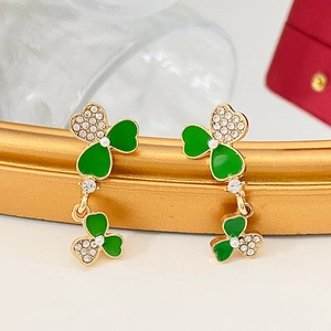 Detalle de pendientes de trébol con esmalte verde, cristales blancos y perlas