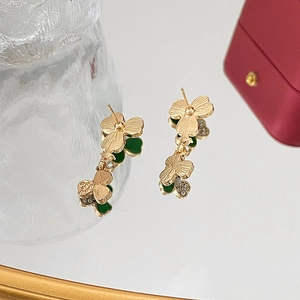 Detalle de pendientes de trébol en oro con incrustación verde y piedras en espejo