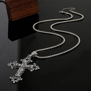 Detailed macro view of an antique silver gothic cross pendant with baroque floral patterns