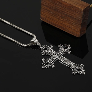Macro shot of antique silver Gothic cross pendant with intricate floral relief details