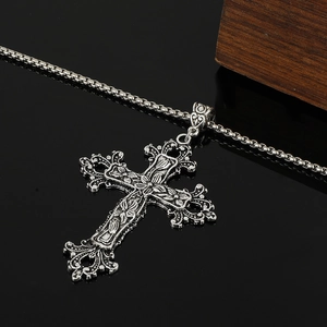 Detailed close-up of Gothic antique silver cross pendant with floral vine carvings