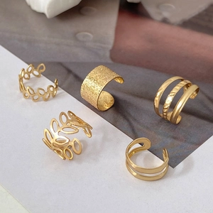 Detail view of five gold-plated ear cuffs featuring hollow leaves and textured finishes
