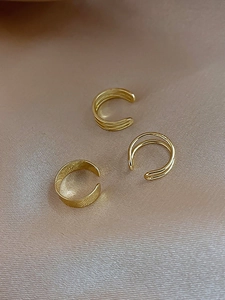 Detailed shot of three gold-plated textured ear cuffs on elegant champagne silk fabric