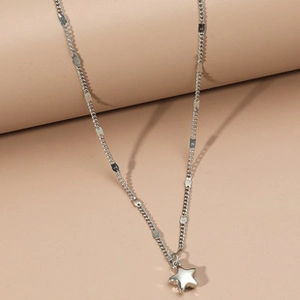 Macro shot of a silver star pendant with a unique chain on a minimalist beige background