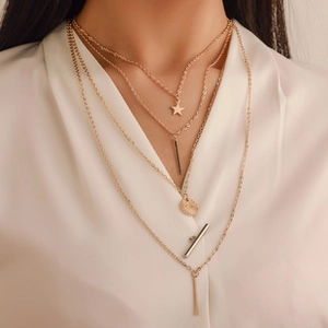 Detail of 4-layer gold layered necklace with star and vertical bar pendants on a model