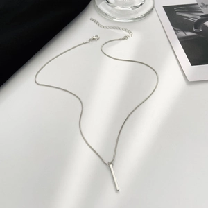 Close-up of minimalist silver spiral pillar pendant on thin snake chain with lobster clasp