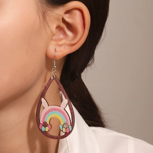Primo piano di orecchini pasquali in legno con design a coniglio arcobaleno indossati da modella