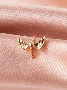 Detailed macro view of gold bat wing ear cuff placed on soft pink satin fabric
