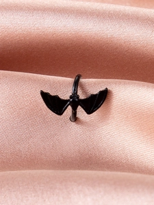 Detailed close-up of dark gothic bat ear cuff on elegant champagne satin background