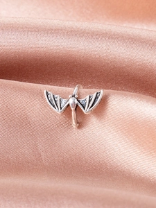 Macro shot of silver bat ear cuff with gothic vintage finish on satin fabric