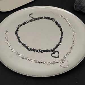 Detailansicht der schwarzen und silbernen Herzketten mit Dornen-Design auf Metalltablett