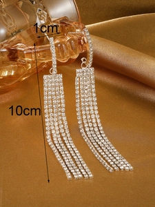 Detalle de pendientes largos de 10cm con borlas de cristal sobre un cristal