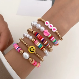Detail of colorful polymer clay Heishi beads and smile face charms on layered bracelets