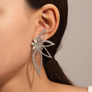 Primer plano de aretes de flores grandes con cristales brillantes en el lóbulo de oreja