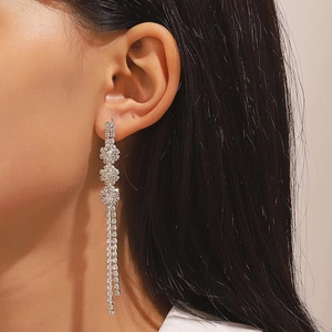 Primer plano de pendientes plateados con pétalos de cristal y flecos en capas