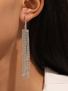 Detalle de pendientes largos de plata con borlas y brillantes pedrería en una modelo
