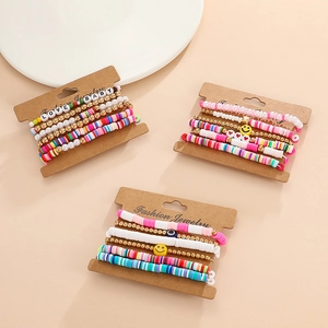 Detailed view of colorful clay beads, alphabet charms and evil eye on layered bracelets