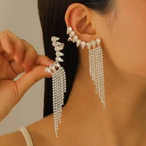 Detalle de pendiente ear cuff plateado con borlas y circonitas puesto en modelo