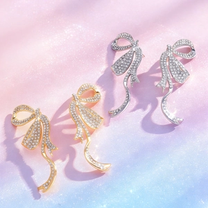 Detalle de pendientes con forma de lazo y diamantes de imitación en oro y plata brillante