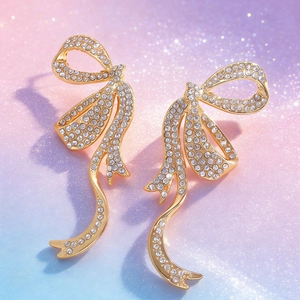 Primer plano detallado de pendientes de lazo dorado con brillantes de imitación blancos