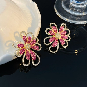 Pendientes de flores huecas doradas con diamantes de imitación rosas y blancos en fondo oscuro