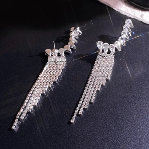 Macro view of silver leaf tassel earrings with sparkling rhinestones on black background