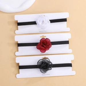 Three elegant vintage rose chokers in white, red, and black velvet on display cards