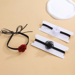 Detailed view of three vintage-style fabric rose chokers in red, black, and white colors