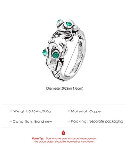 Macro shot of vintage silver frog ring with green gem eyes and technical specs