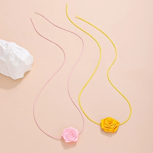 Macro detail of pink and yellow fabric rose chokers with thin minimalist tie-up cords