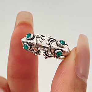 Detailed close-up of retro frog ring featuring green gemstones and vintage silver finish