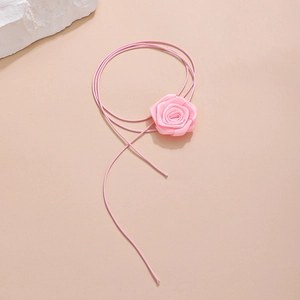 Detail of pink satin rose fabric choker with soft cord on a minimalist warm background