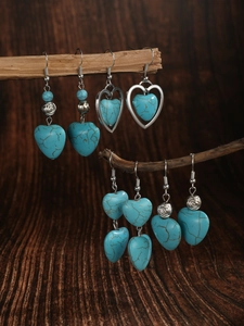 Detail of bohemian turquoise heart earrings hanging on a natural wooden branch