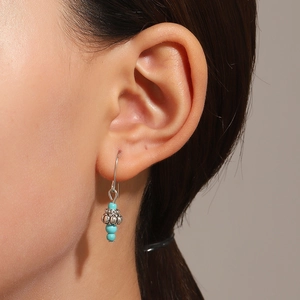 Detail shot of vintage Bohemian silver earrings with turquoise beads on female model