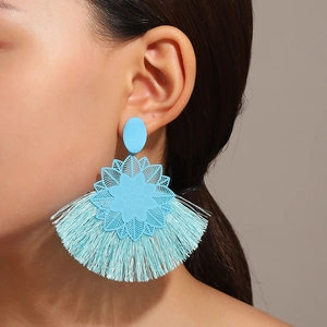Detalle de pendientes boho de flores azul claro con borlas de tela en modelo femenina