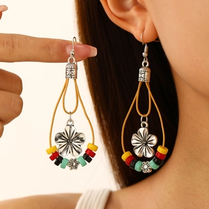 Detail of bohemian drop earrings with turquoise beads and silver sunflower pendant charms